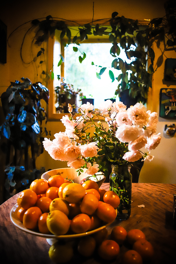 The kitchen is filled with flowers and fruit and the presence of family